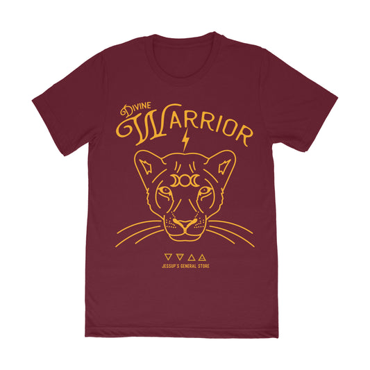 A maroon-colored unisex t-shirt featuring a graphic of a lion's face with the text 'Divine Warrior' and cosmic symbols in a golden color.